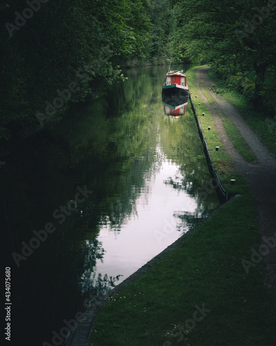 canal barge mored locally, vibrant greens and strong reflections in the water