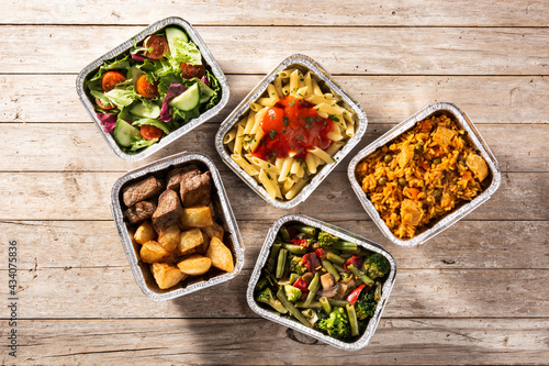 Take away healthy food in foil boxes on wooden table. Top view