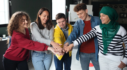 Group of people stacking hands together in community center, inclusivity and unity concept.