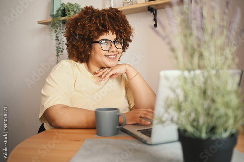 Attractive happy stylish plus size African black woman student afro hair in glasses studying online working on laptop computer at home office workspace. Diversity. Remote work, distance education photo