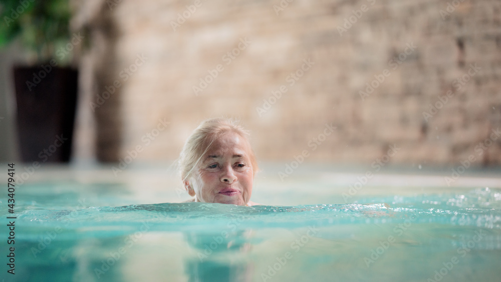 Portrait of senior woman in indoor swimming pool, swimming.