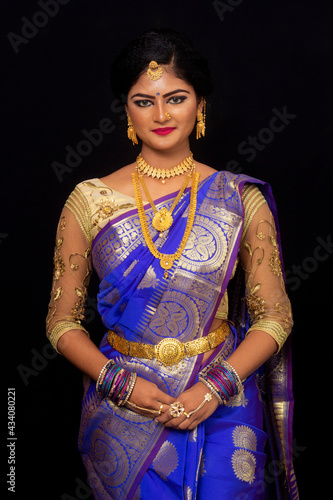 Indian woman in bridal look in blue saree with jewelry looking at camera