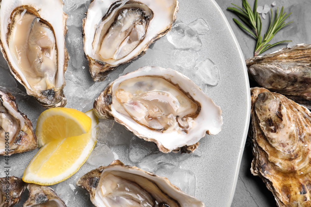 Delicious fresh oysters with lemon slices served on table, closeup Delicious fresh oysters with lemon slices served on table, closeup