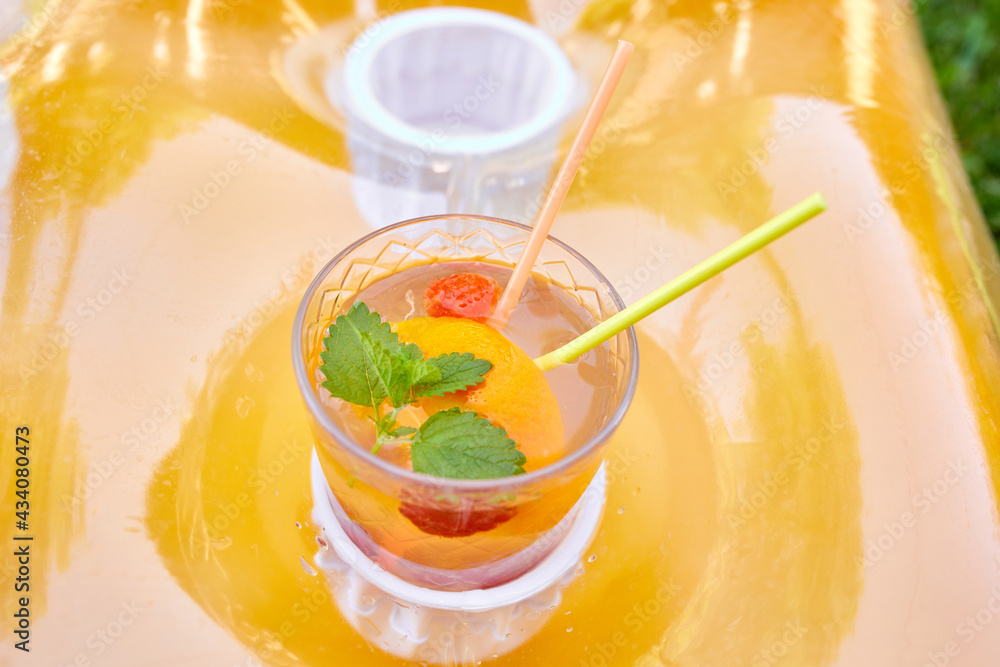 Summer background, Lemonade drink, Cold and refreshing orange punch cocktail on an inflatable mattress Summer background, Lemonade drink, Cold and refreshing orange punch cocktail on an inflatable mattress