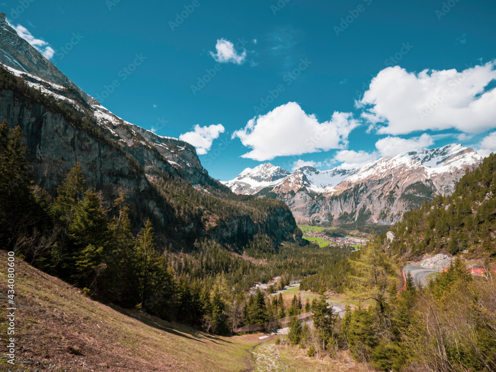 Beautiful alpine view of high snow capped mountains, pine forest trees and vast mountainous landscape. Kandersteg, Switzerland.