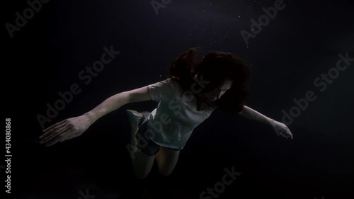 an adult woman with no signs of life as in space the body hovers in the weightlessness of water photo