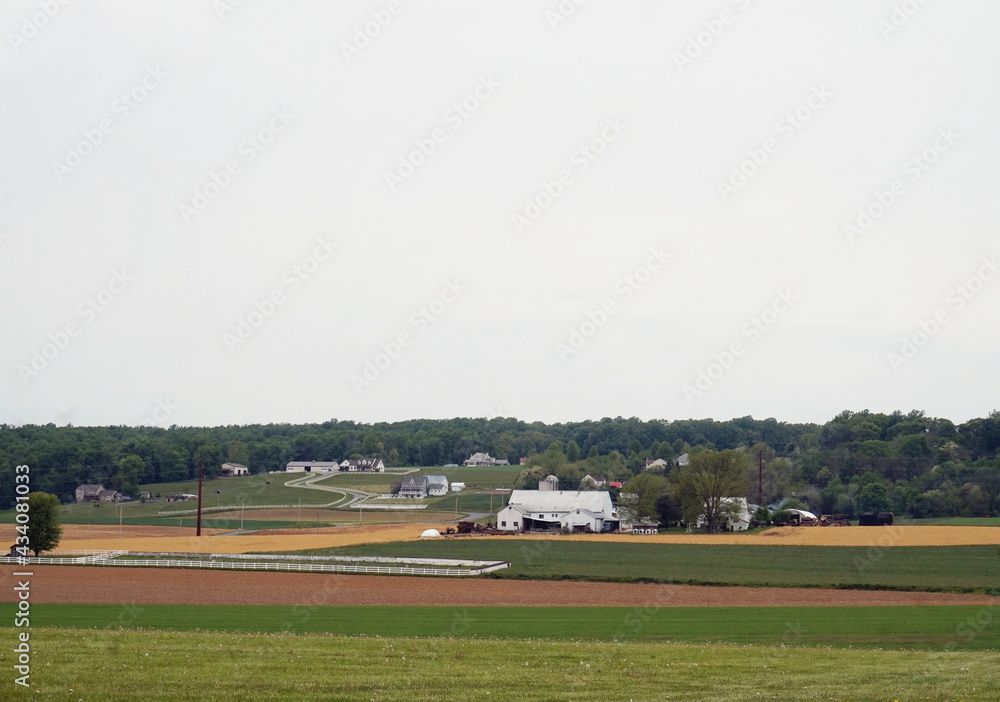 Village of Homes and Farm Buildings in the Midst of Green and Plowed Farm Fields in Daylight Village of Homes and Farm Buildings in the Midst of Green and Plowed Farm Fields in Daylight
