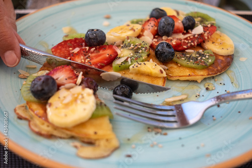 Close-up on healthy summer breakfast, classic american pancakes with banana, kiwi, fresh berry and honey