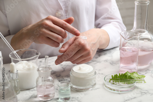 Scientist testing cosmetic product at white marble table in laboratory  closeup