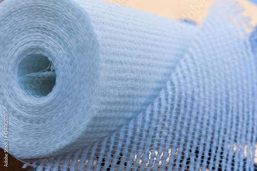 A slightly unfolded roll of fiberglass Wallpaper. Shooting against the light. Selective focus.