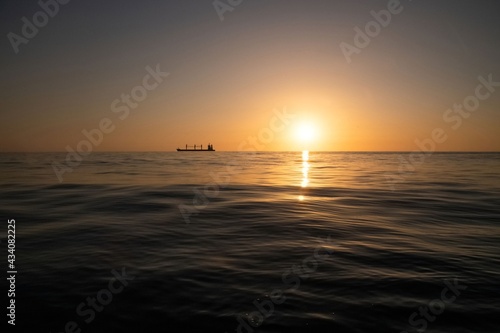 Silhouette of a freight ship on the horizon of the Mediterranean sea during sunset