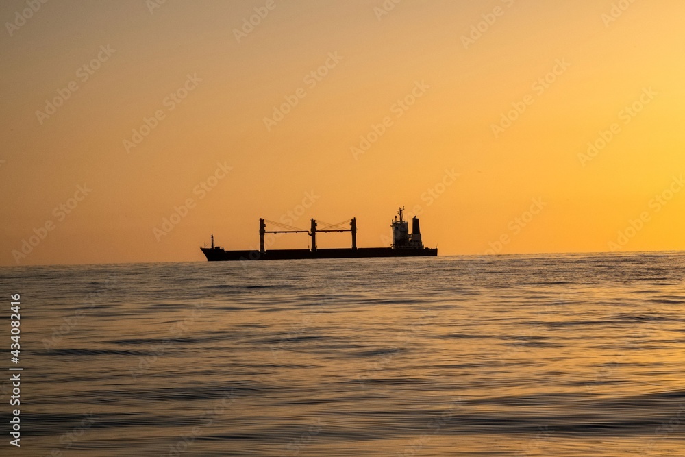 Silhouette of a freight ship on the horizon of the Mediterranean sea during sunset Silhouette of a freight ship on the horizon of the Mediterranean sea during sunset