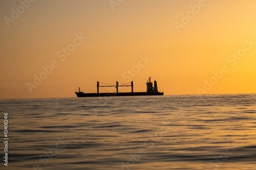 Silhouette of a freight ship on the horizon of the Mediterranean sea during sunset