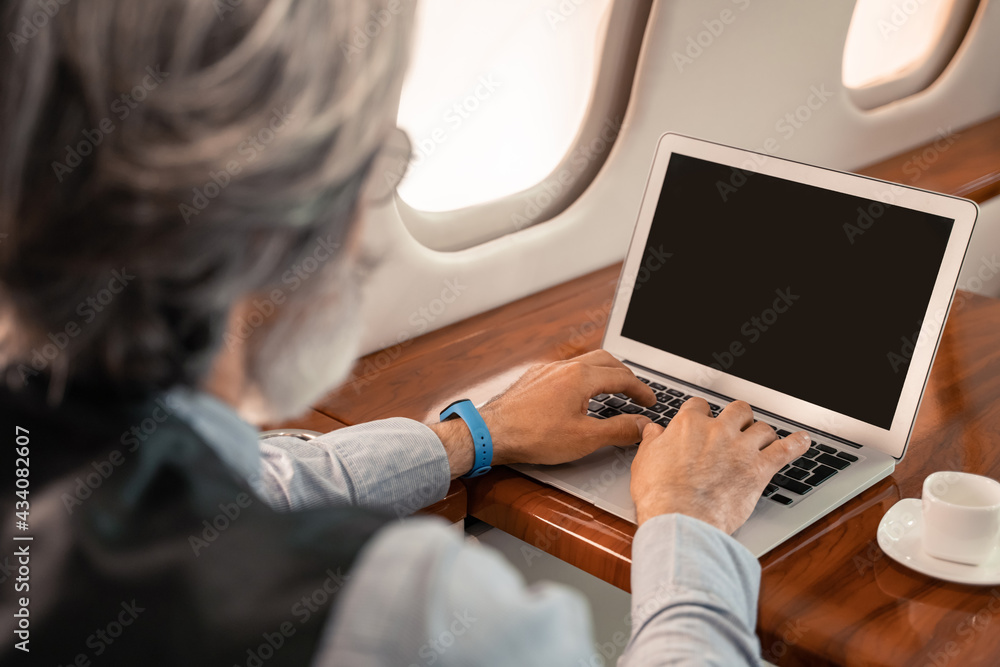 Blurred businessman using laptop near coffee in jet plane Blurred businessman using laptop near coffee in jet plane