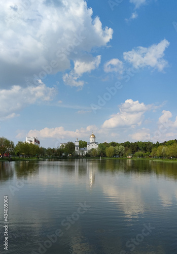 Scenic view of a park with a reservoir in the center of a big city in spring. A pond in the park in the middle of green trees. Rest in the city, oasis.