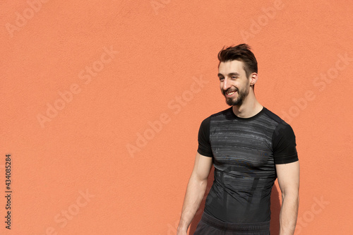 young athletic man in sports clothes on a terracotta background