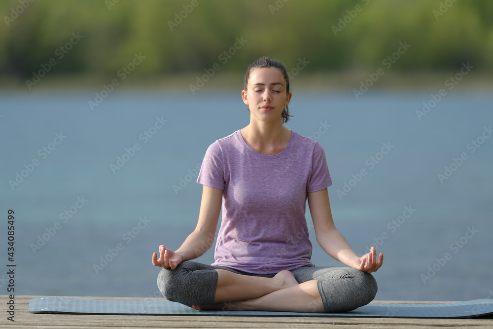 Woman doing yoga lotus pose in a lake