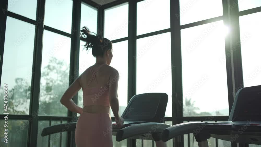 Rear view of Healthy young woman jogging on treadmill at health club. Female working out at a gym running on a treadmill. Rear view of Healthy young woman jogging on treadmill at health club. Female working out at a gym running on a treadmill.