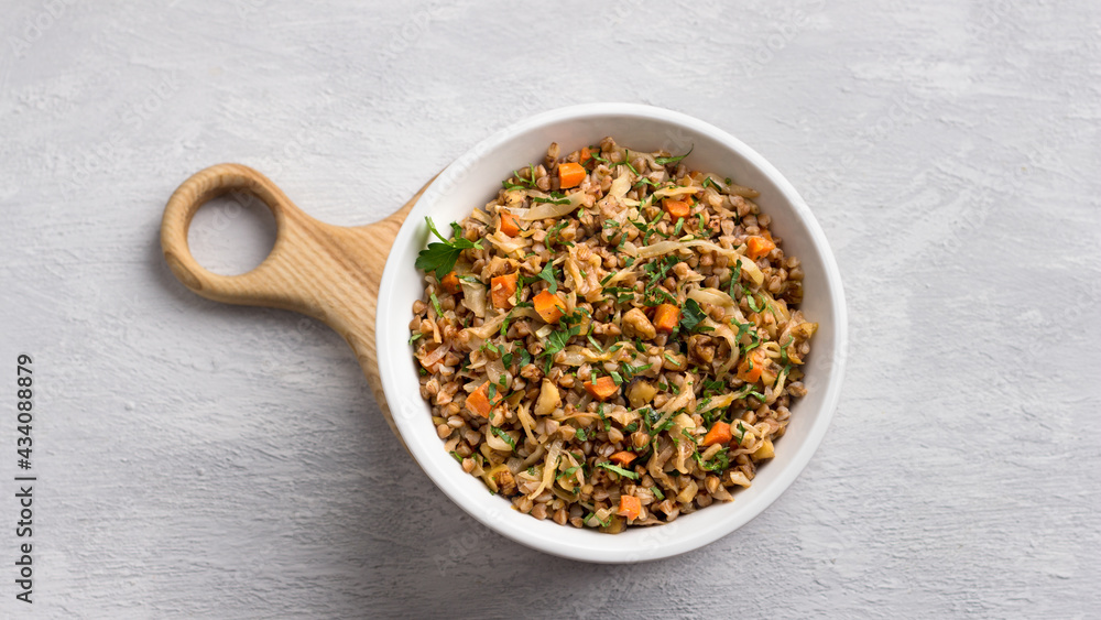 Delicious vegetarian buckwheat with cabbage, carrots, onions, nuts and herbs on a light gray textured background, top view. Homemade diet healthy food Delicious vegetarian buckwheat with cabbage, carrots, onions, nuts and herbs on a light gray textured background, top view. Homemade diet healthy food