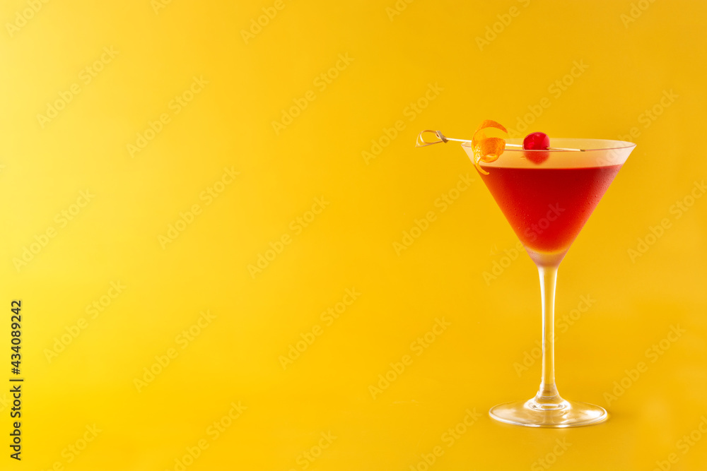 Traditional Manhattan cocktail with cherry on yellow background. Copy space
