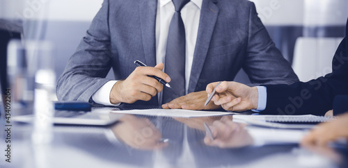 Unknown business people working together at meeting in modern office, close-up. Businessman and woman with colleagues or lawyers discussing contract at negotiation