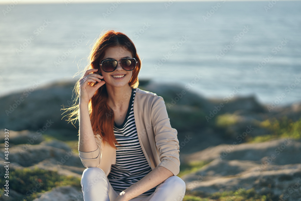woman on a high stone in the mountains near the sea and glasses on her face summer vacation travel woman on a high stone in the mountains near the sea and glasses on her face summer vacation travel