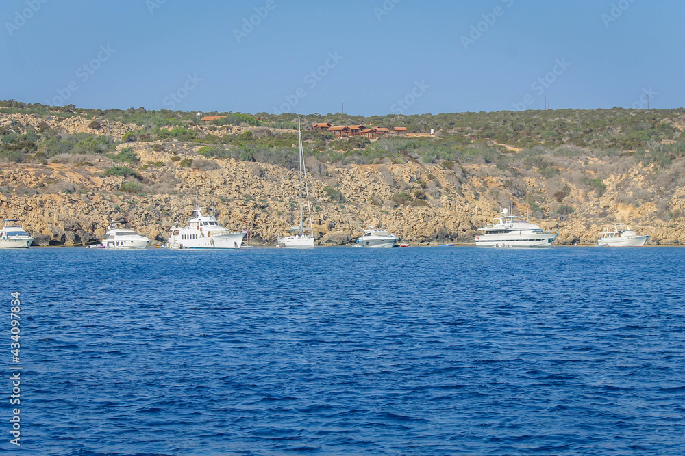 Yachts are lined up along the coastline, view from the sea