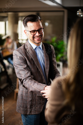 Businesswoman and businessman discussing work in office. Two friends handshake in office