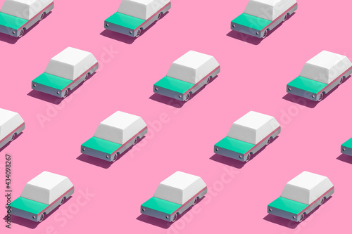 Minimal retro future car concept pattern wtih teal green cars on bright vibrant neon pink background. Trendy bold summer travel and road trip idea. Retro aesthetic.