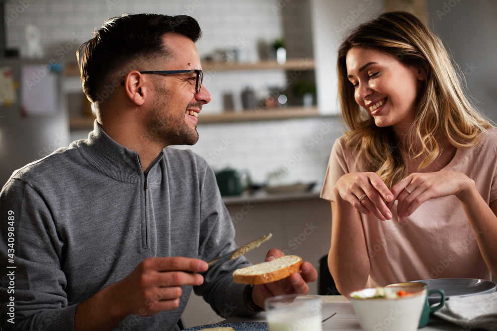 Beautiful young girl enjoying in breakfast with her boyfriend. Loving couple drinking coffee in the kitchen Beautiful young girl enjoying in breakfast with her boyfriend. Loving couple drinking coffee in the kitchen