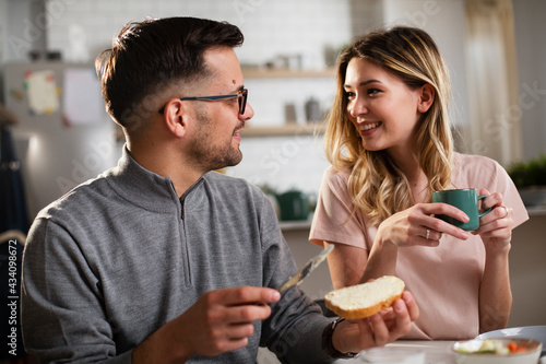 Beautiful young girl enjoying in breakfast with her boyfriend. Loving couple drinking coffee in the kitchen