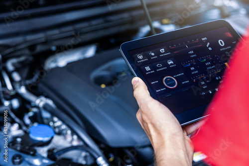 car service mechanic using digital tablet with diagnostics software to check engine condition. vehicle inspection photo