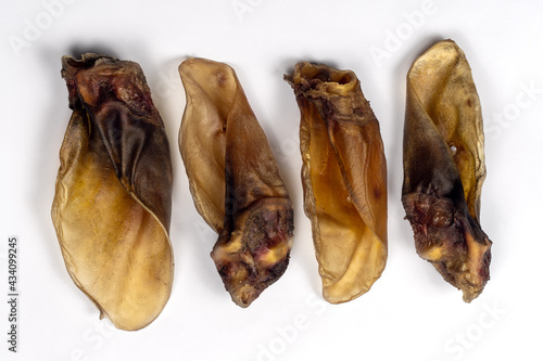 Four pieces pf dehydrated organic beef ears made for dogs. Homemade meat pet treats, dry chew jerky. White background, closeup, copy space.