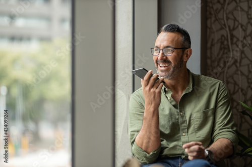 Fotografie, Obraz wide shot mature man with beard talking on phone next to sunny window