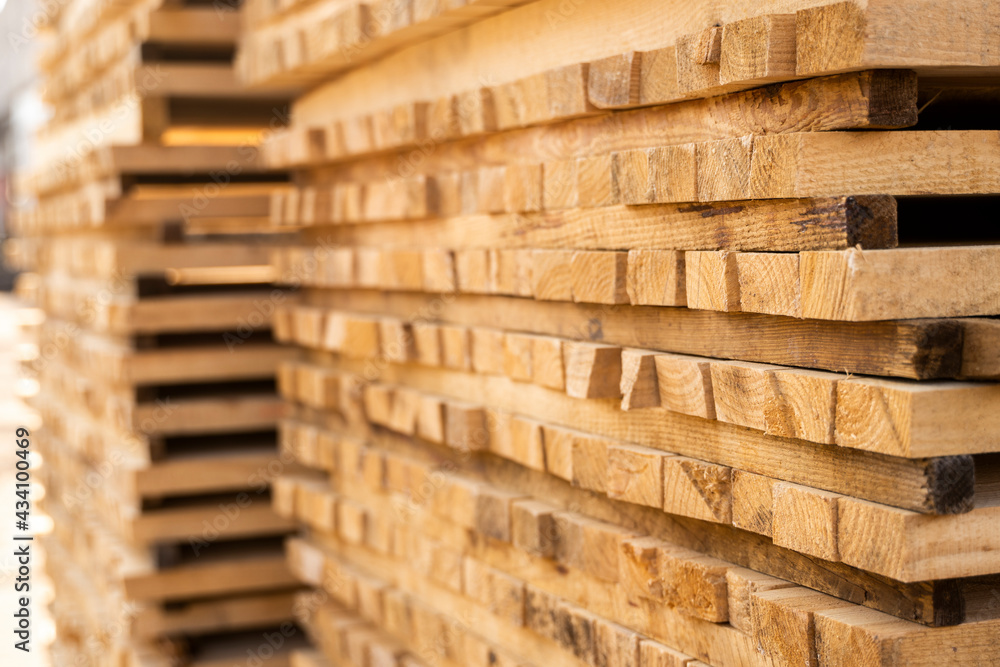 Storage of piles of wooden boards on the sawmill. Boards are stacked in a carpentry shop. Sawing drying and marketing of wood. Pine lumber for furniture production, construction. Lumber Industry. Storage of piles of wooden boards on the sawmill. Boards are stacked in a carpentry shop. Sawing drying and marketing of wood. Pine lumber for furniture production, construction. Lumber Industry.