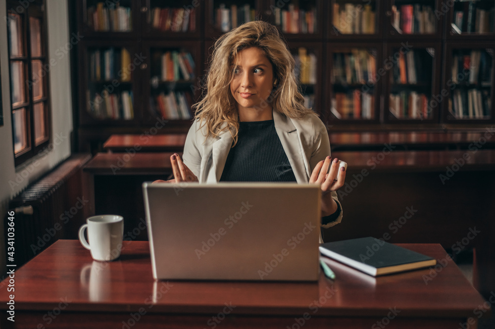 Businesswoman using a laptop for an online meeting while working in her office Businesswoman using a laptop for an online meeting while working in her office