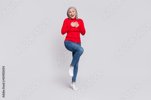 Full size photo of excited aged woman happy positive smile hands on chest amazed surprised laugh isolated over grey color background