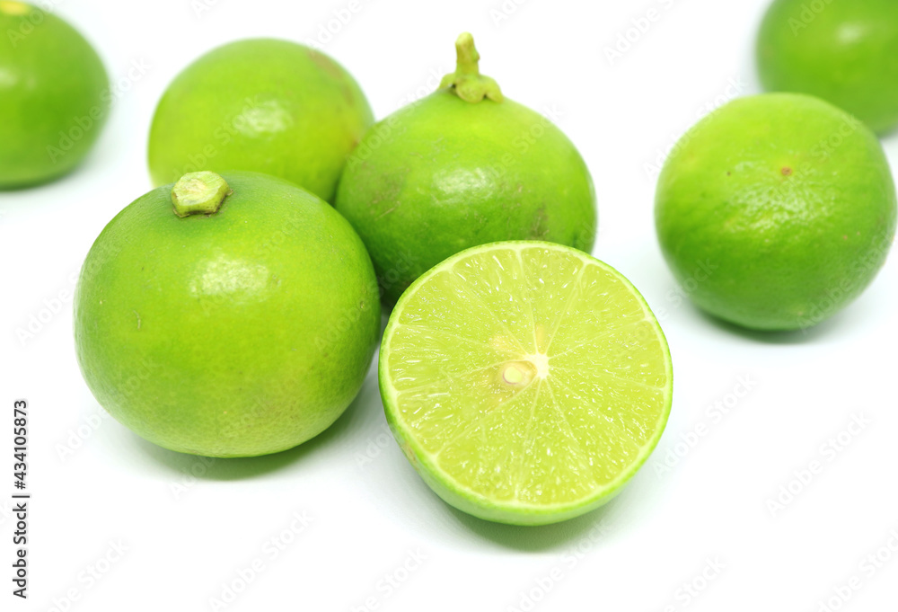 Closeup half cut vibrant green fresh lime with the whole fruits scattered on white backdrop Closeup half cut vibrant green fresh lime with the whole fruits scattered on white backdrop