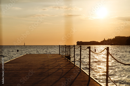 Picturesque seaside resort town in Slovenian coast against orange sunset sky in summer. Scenic view to Adriatic sea in the evening. Travel concept. 