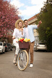 Lovely couple with bicycle and flowers on city street