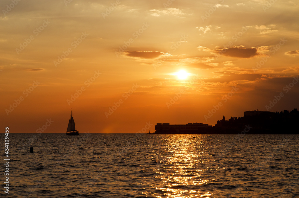 Picturesque seaside resort town in Slovenian coast against orange sunset sky in summer. Scenic view to Adriatic sea in the evening. Travel concept. 