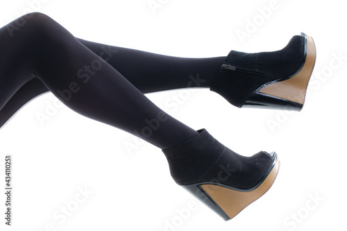 Feet of a young woman in pantyhose with shoes on a white background