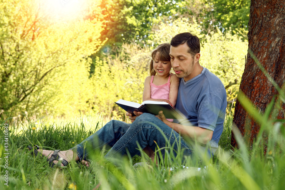 young father with a small daughter reading the Bible young father with a small daughter reading the Bible
