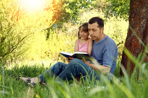 young father with a small daughter reading the Bible
