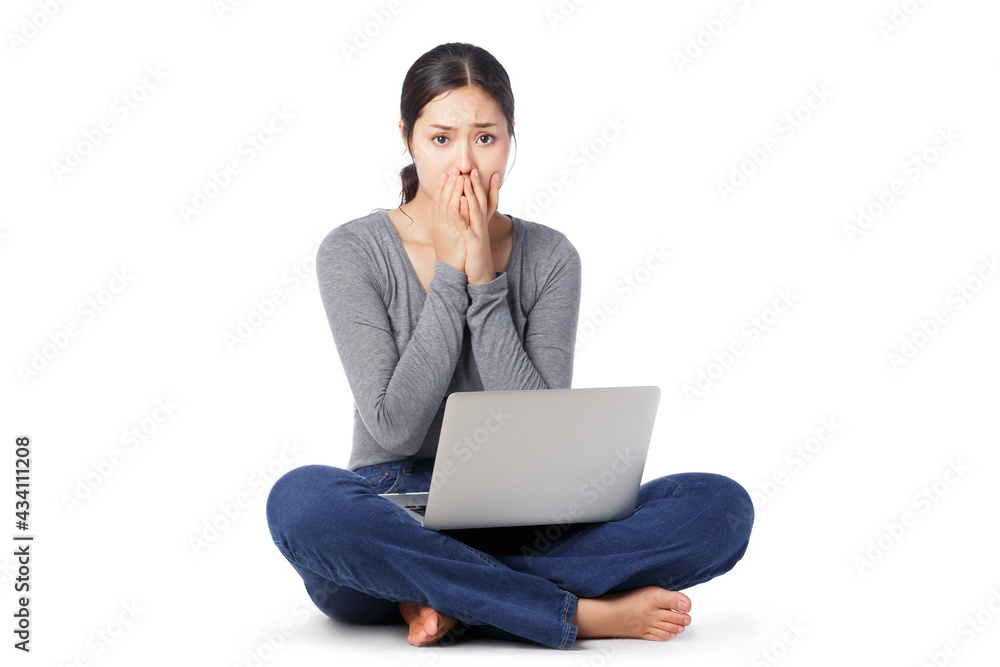 Young happy Asian woman sitting on the floor with laptop computer on her legs isolated on white background. Attractive freelancer covering mouth by her hands with big eyes open Amazed or shocked Young happy Asian woman sitting on the floor with laptop computer on her legs isolated on white background. Attractive freelancer covering mouth by her hands with big eyes open Amazed or shocked