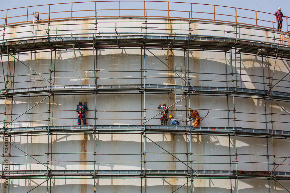 Construction workers tank oil installing scaffolding