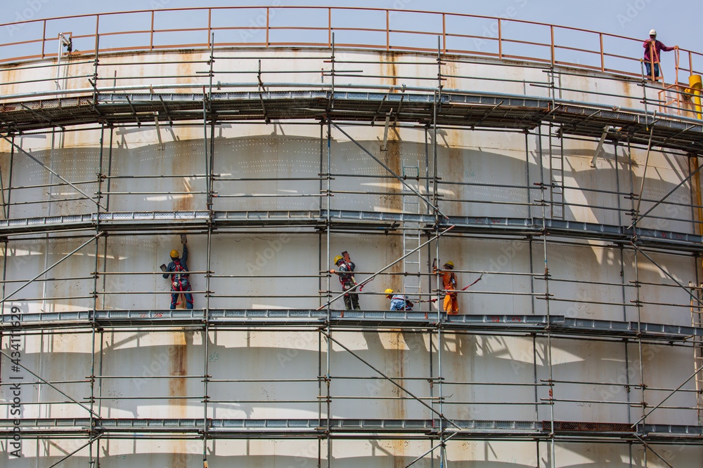 Construction workers tank oil installing scaffolding Construction workers tank oil installing scaffolding