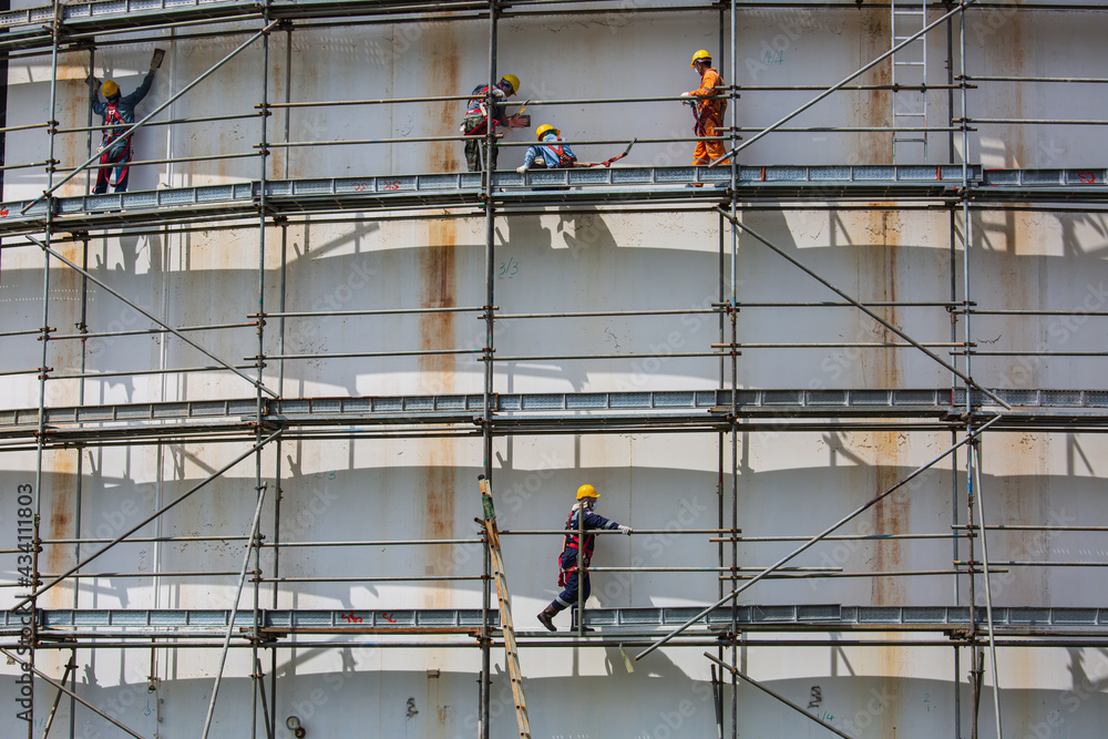 Construction workers tank oil installing scaffolding Construction workers tank oil installing scaffolding
