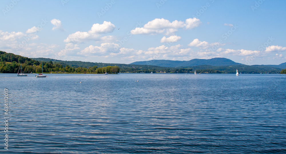 Fototapeta premium Blue sky and puffy white clouds over calm Lake Memphremagog in Vermont, USA