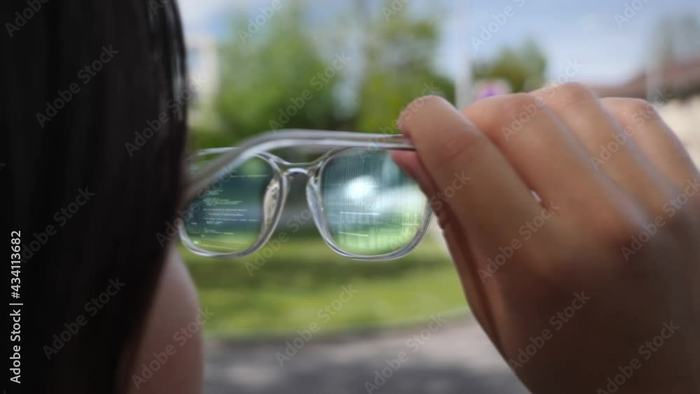 Young woman looks through modern augmented reality glasses with digital display. Concept futuristic help device